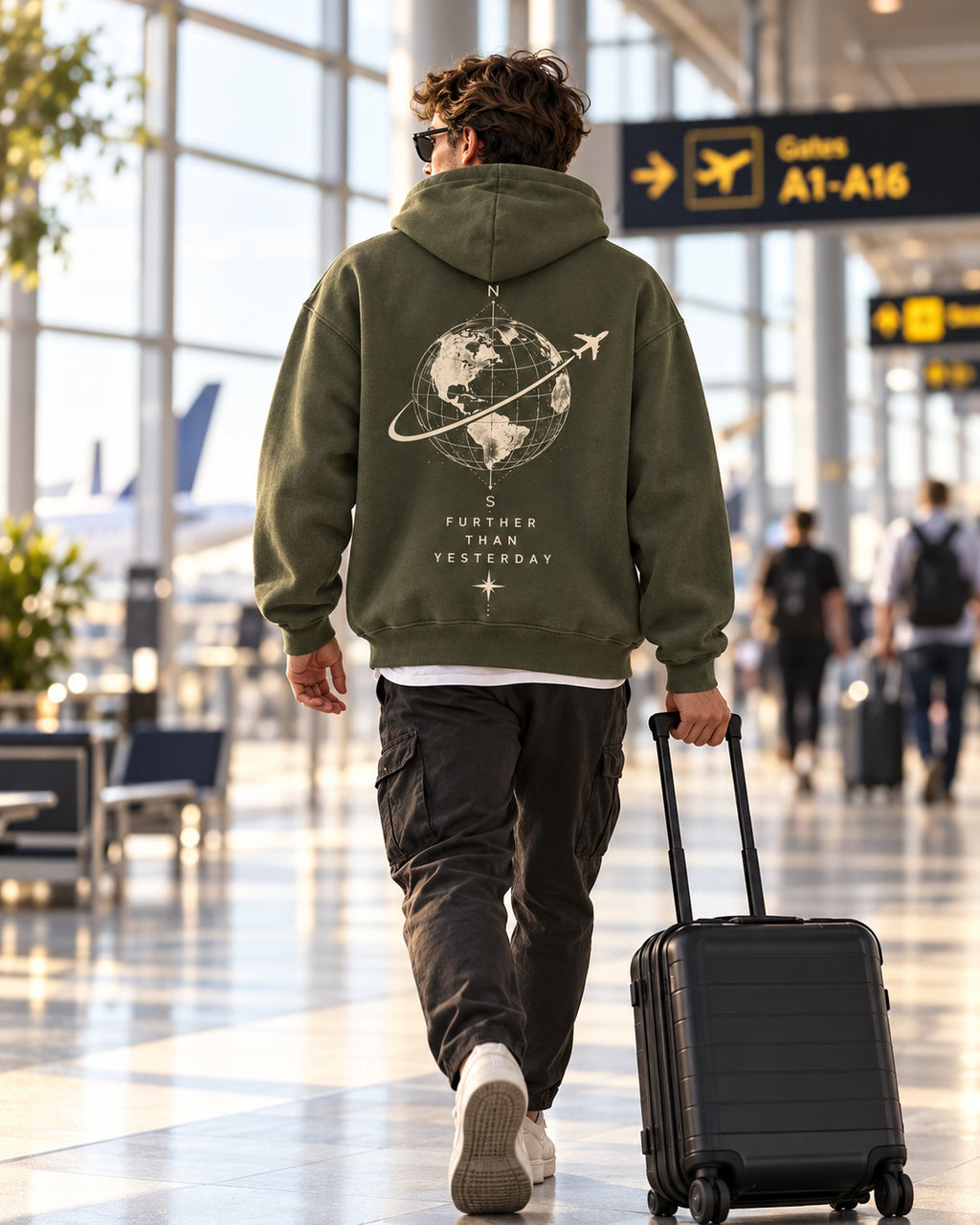 Airport lifestyle photo of traveler wearing olive Further Than Yesterday hoodie